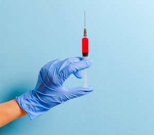 person in a medical glove holds a syringe