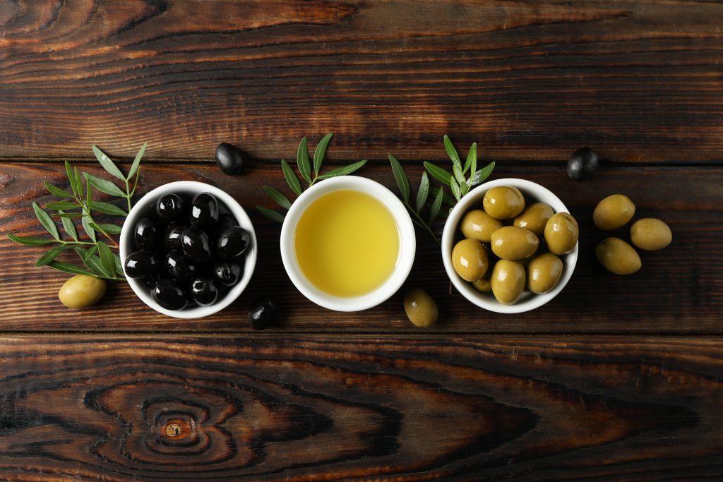 black olives, green olives, olive oil served in bowls on a table